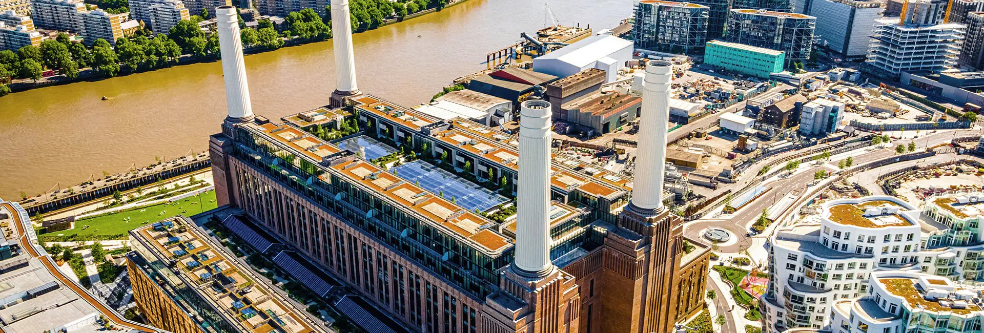 Aerial view of the Battersea Power Station, a large brick building with four tall white chimneys.